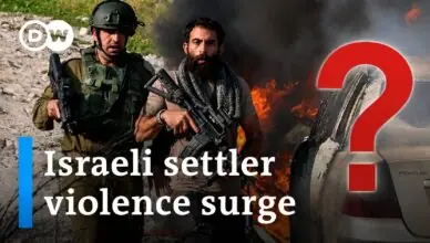 Two armed men walk past a burning car in a desolate area, with the headline 'Israeli settler violence surge' overlaid (DW).
