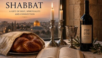Shabbat table with challah, wine, candles, and prayer book against a sunset cityscape backdrop of Jerusalem.